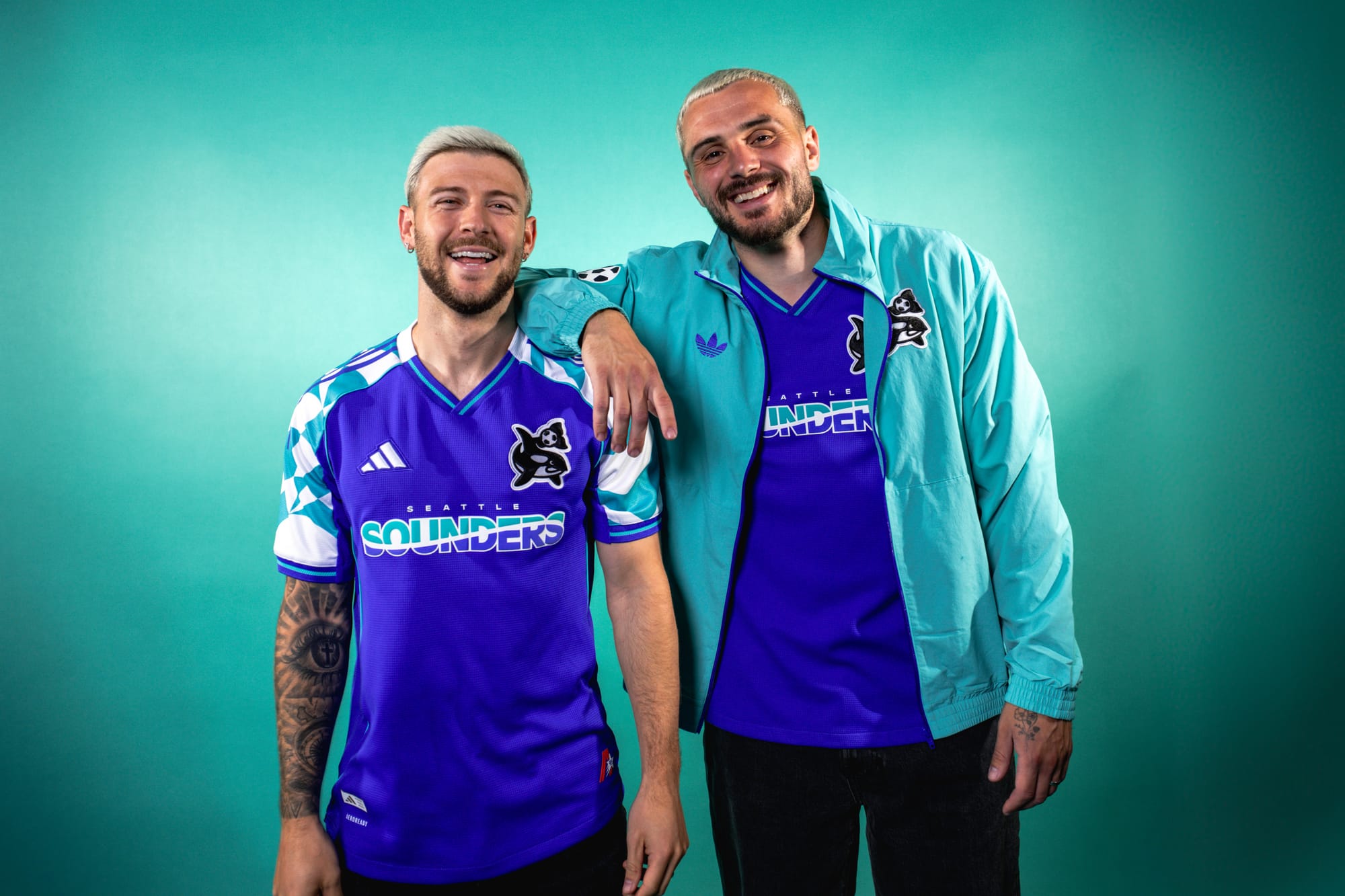 Paul Arriola wears the Orca Kit, Jordan Morris wears an aqua jacket.