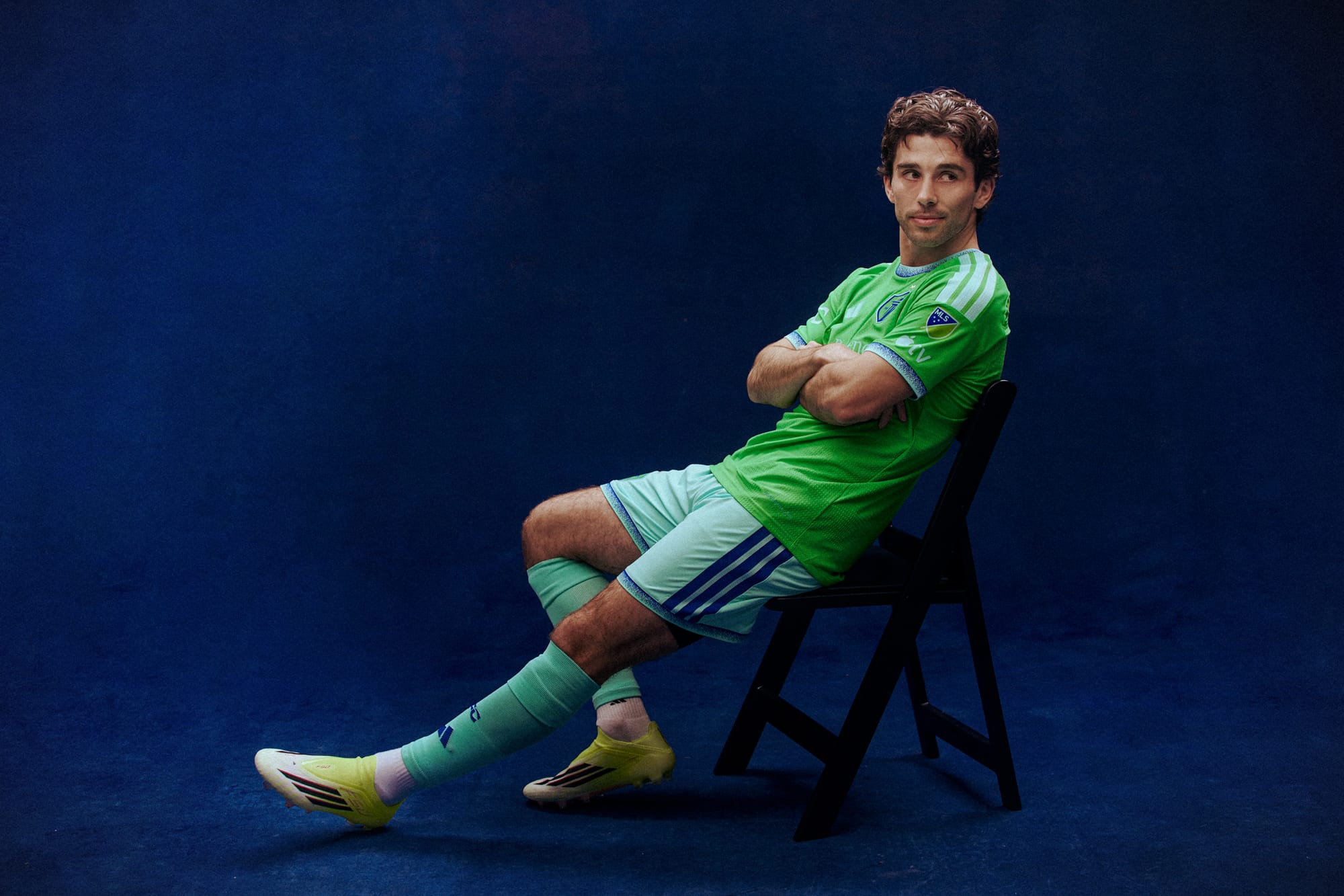Paul Rothrock leaning back in a black folding chair wearing a green Sounders jersey.