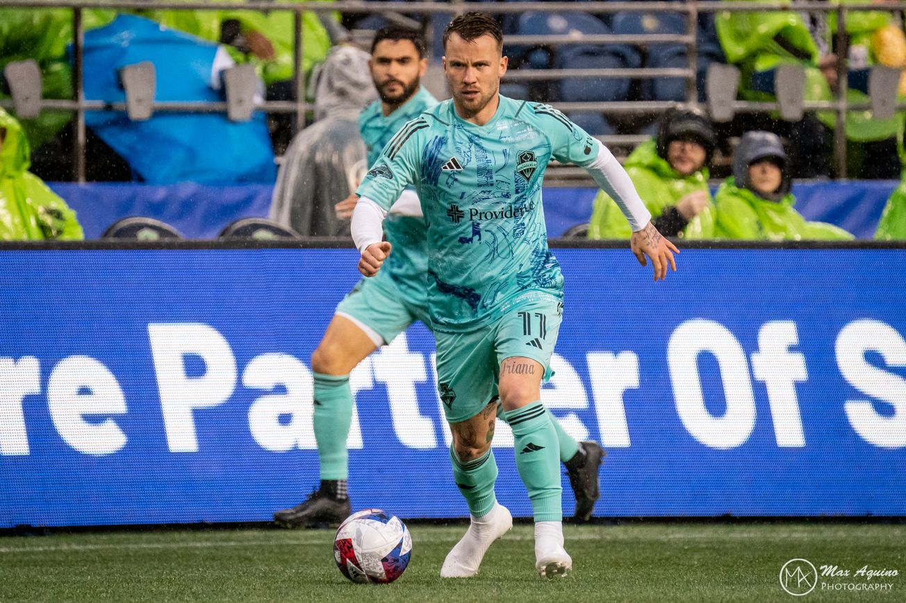 Albert Rusnák dribbles up the pitch. In the background is Alex Roldán. 