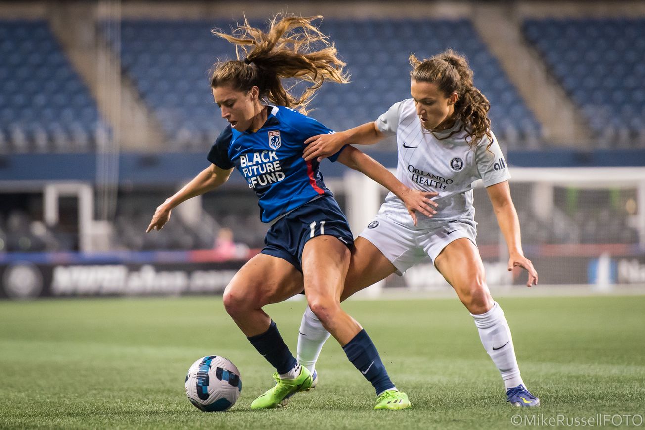 OL Reign's Sofia Huerta has the ball at her feet and is preventing Orlando Pride's Kerry Abello from getting to the b