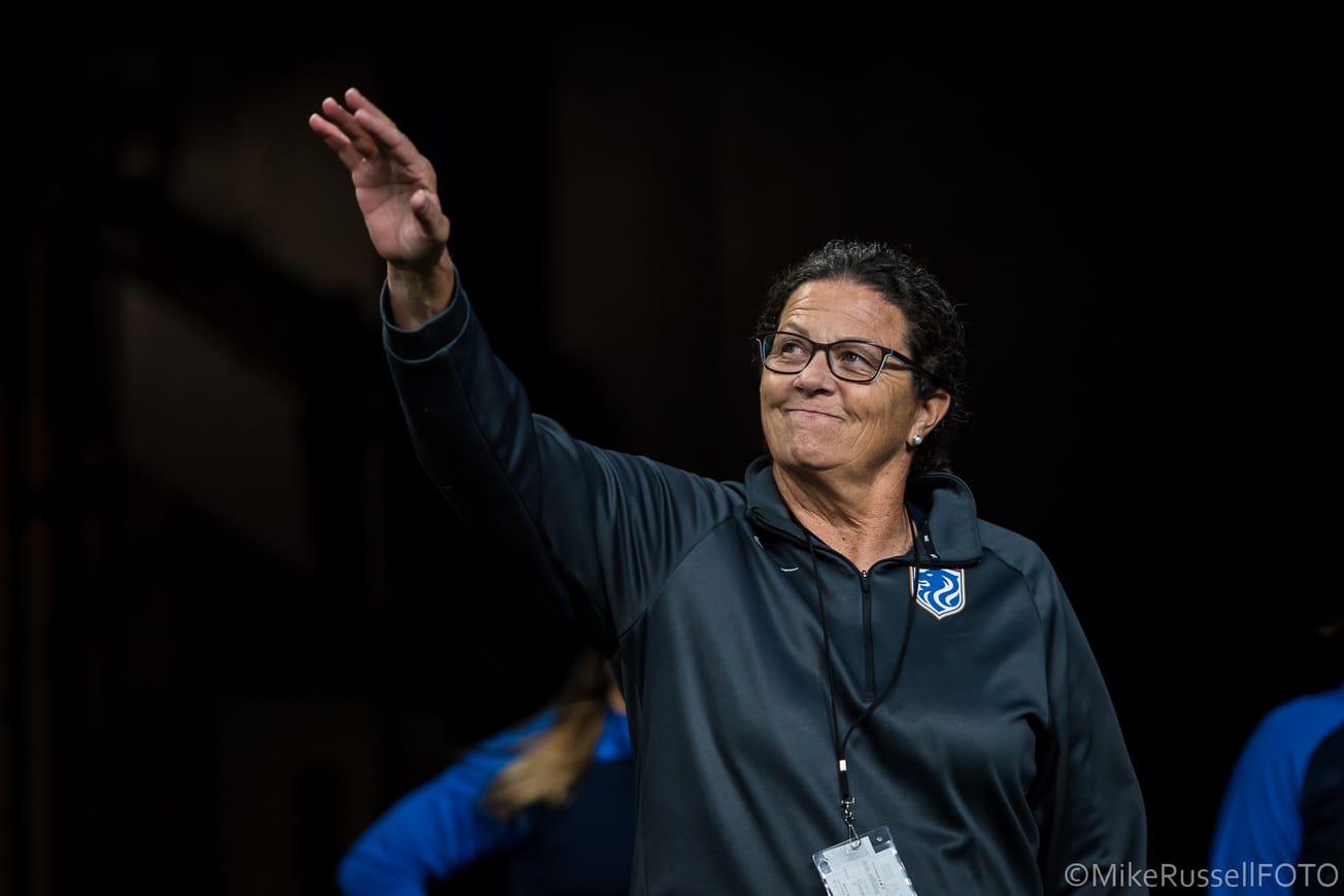 OL Reign general manager Lesle Gallimore waves to fans as she walks out of a Lumen Field tunnel.