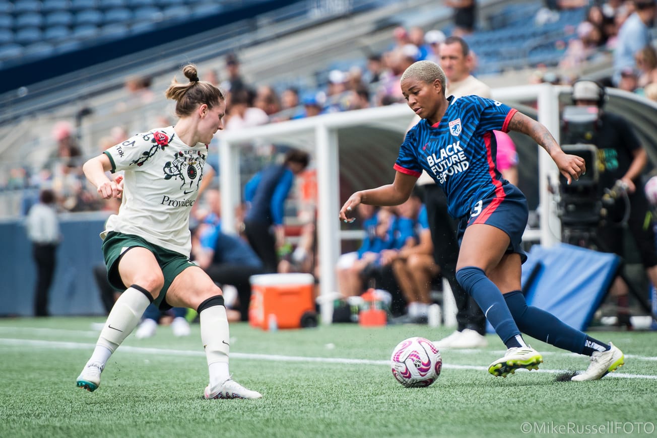 Reign forward Tziarra King takes on a Portland Thorns defender in an August 2023 match.