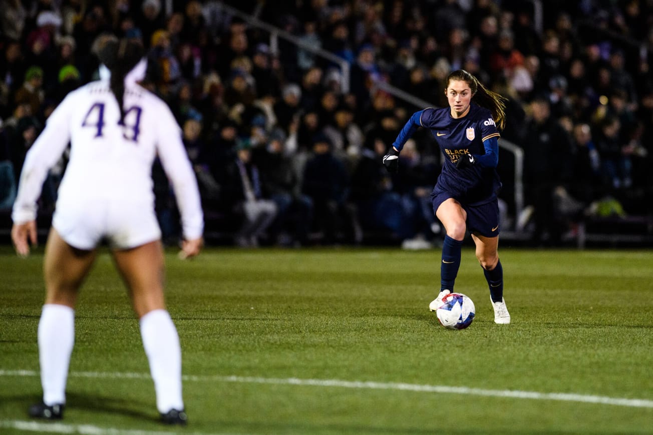 Newly signed Seattle Reign FC midfielder Maddie Mercado takes on a University of Washington defender in a preseason game.