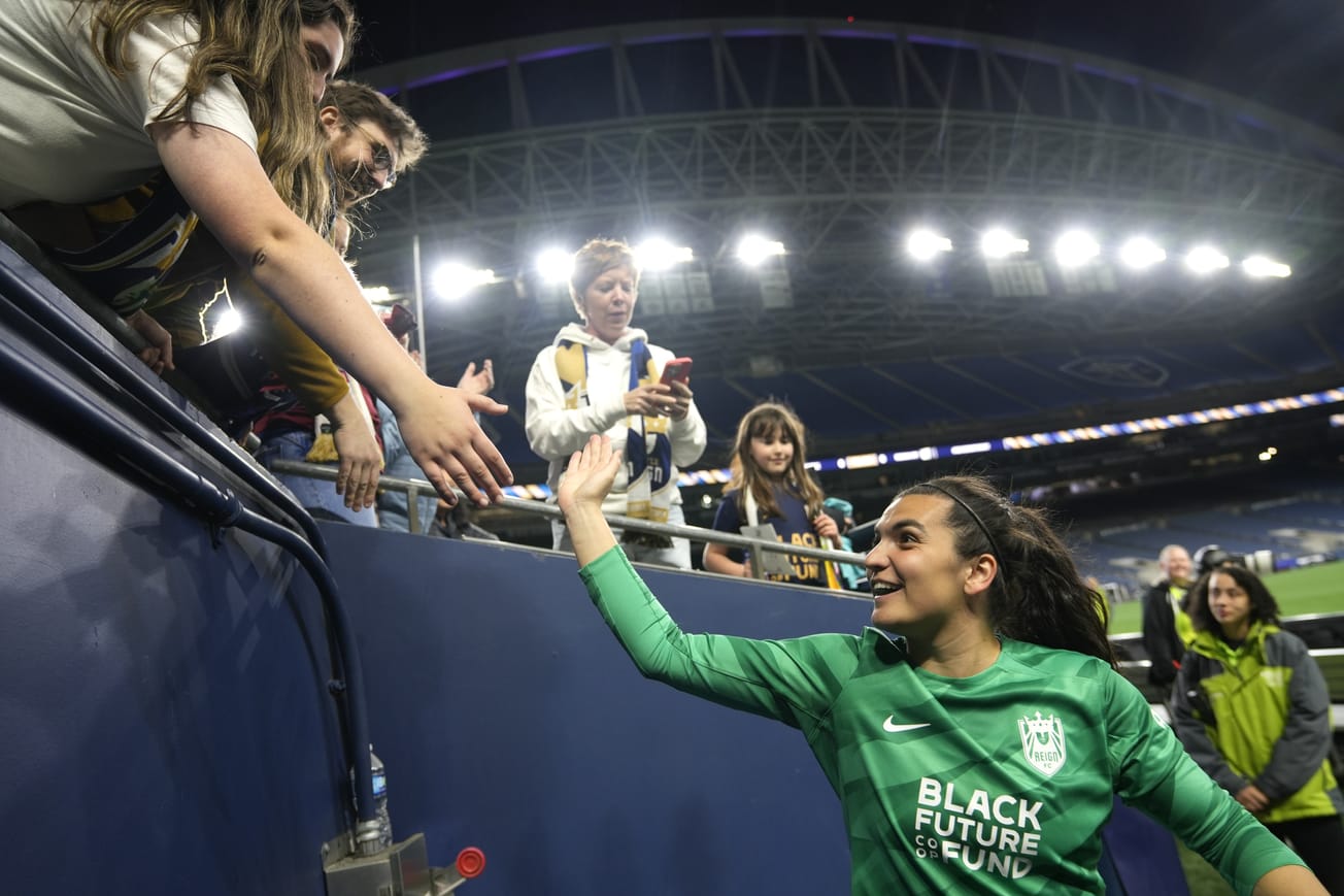 Seattle Reign goalkeeper Laurel Ivory gives a high-five to a fan after a game at Lumen Field.