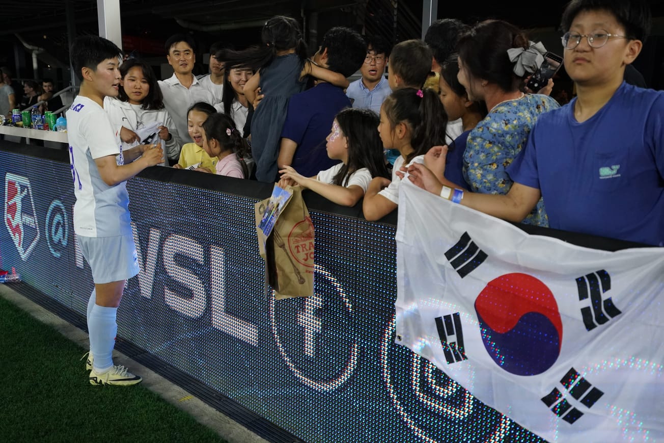 Seattle Reign midfielder Ji So-yun signs autographs for South Korea fans after a game.