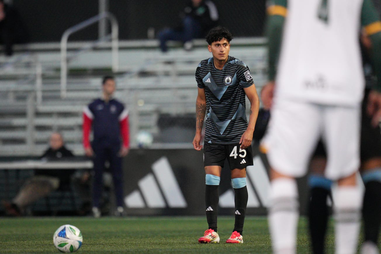 Peter Kingston wearing a black Tacoma Defiance kit stands over a free kick.