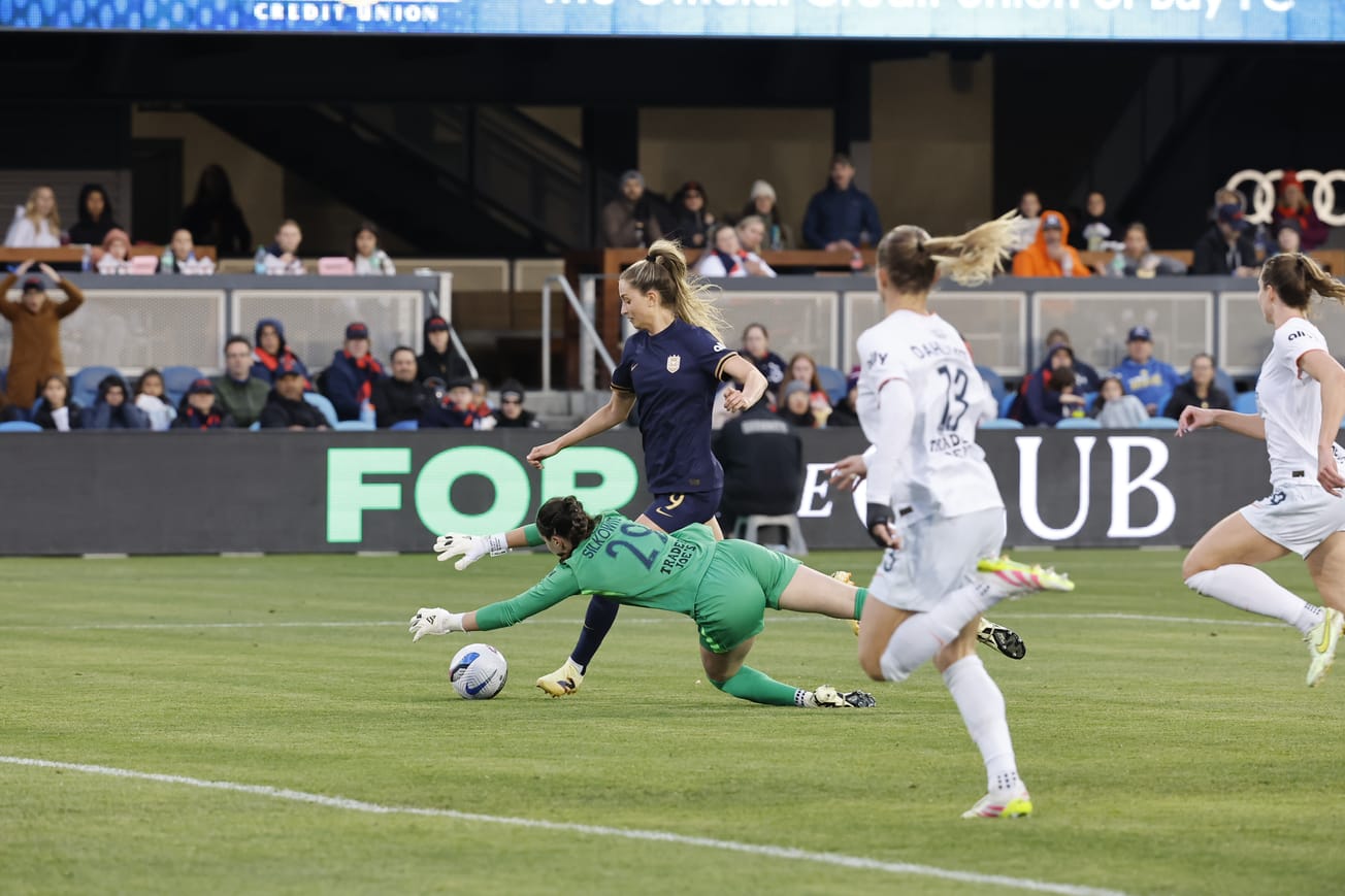 Reign forward Jordyn Huitema attempts to get past Bay goalkeeper Jordan Silkowitz in the first half of an April 2025 match.