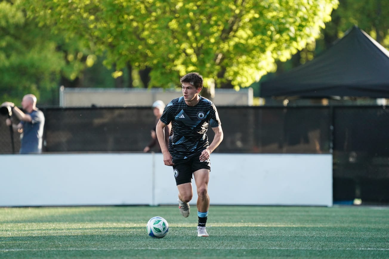 Reed Baker-Whiting running with a ball wearing black Tacoma Defiance kit.