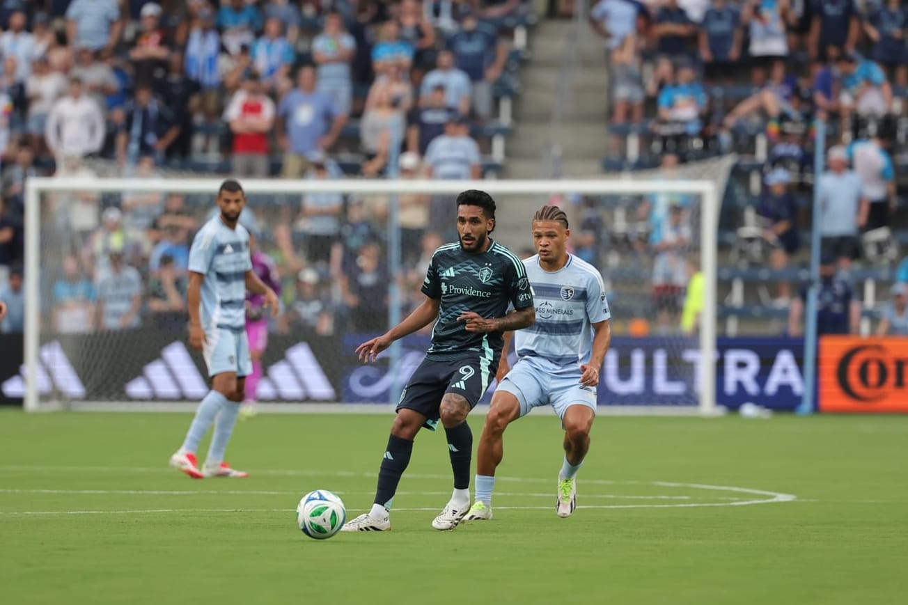Jesus Ferreira in a dark blue Sounders kit receives the ball in midfield.