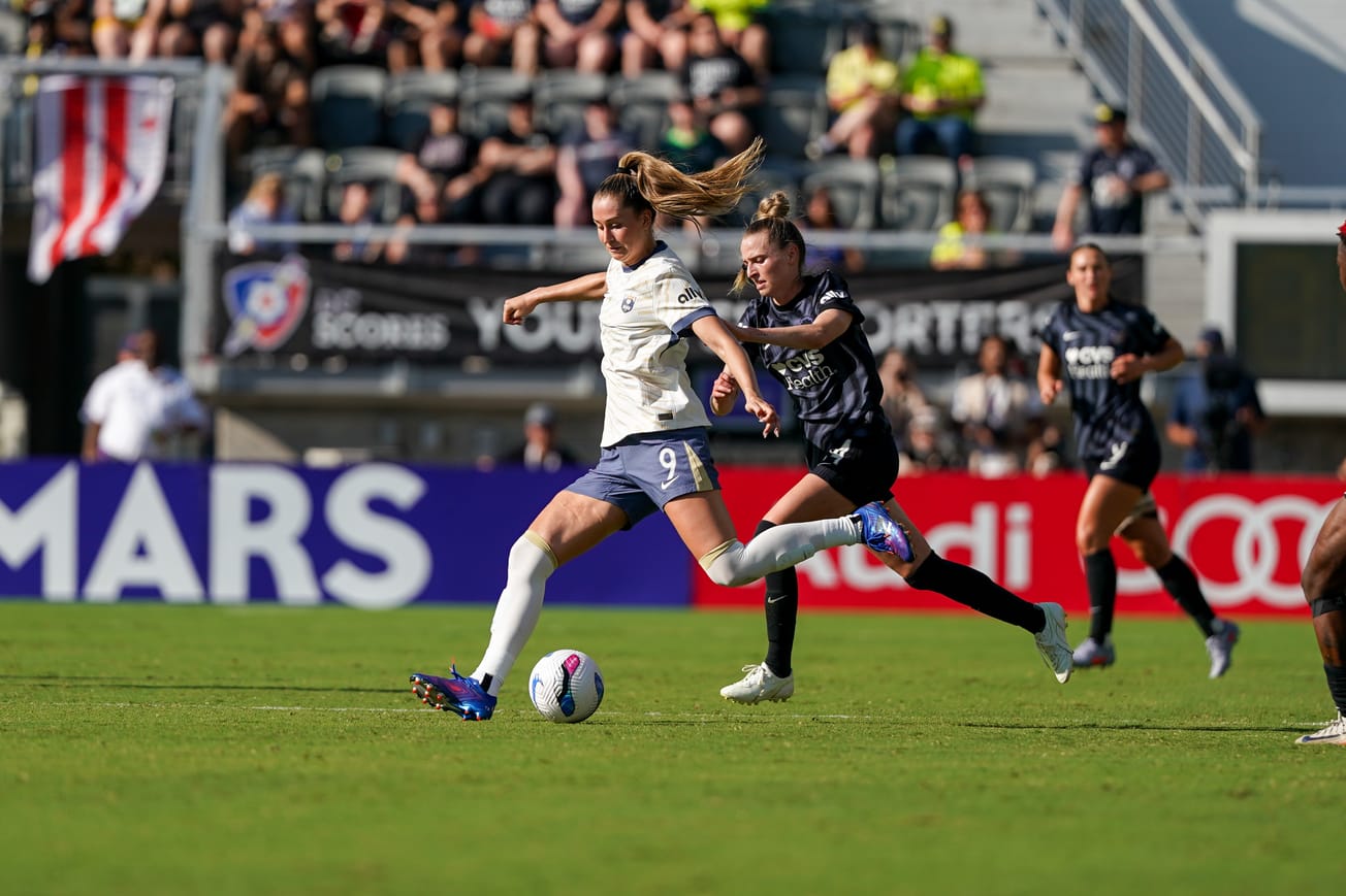 Reign forward Jordyn Huitema winds up to kick the ball as a Washington Spirit defender pressures her in an August 2025 match.