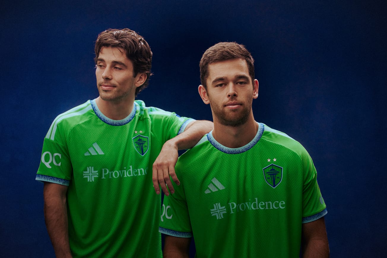 Paul Rothrock rests an arm on Jackson Ragen’s shoulder, both wear a green Sounders jersey 